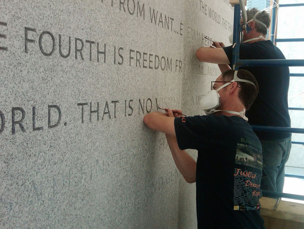Nick Benson and Paul Russo apply a tint to the lettering at Four Freedoms Park in New York.