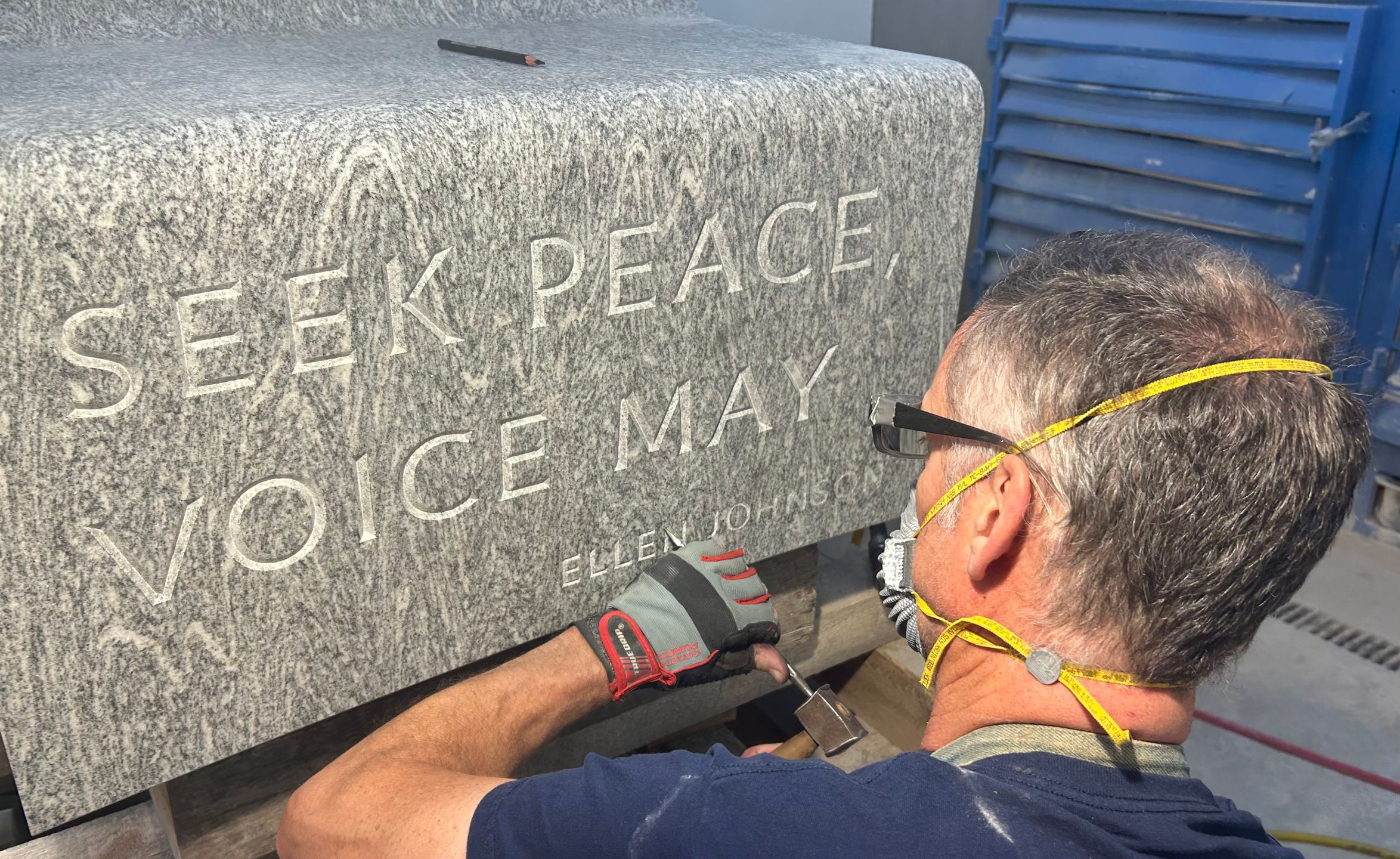 Master stone carver Nick Benson hand-chisels lettering for the inscriptions on the benches of Peace Corps Park